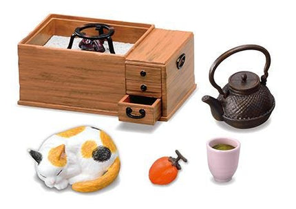 a wooden box with a teapot, a ceramic cup, a ceramic bowl, a ceramic figurine of a cat, and a ceramic fruit.