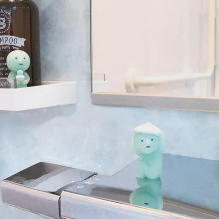 a bathroom shelf with two bottles of shampoo and three small figurines, likely representing a character or mascot, placed on it.
