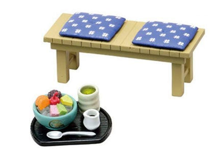 a small wooden bench with two blue cushions, and a tray with a bowl of food and a cup on it.