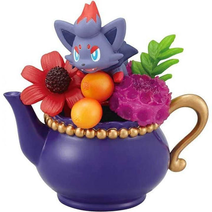 A purple teapot with a gold handle and a small figurine of a cat sitting on top of it.