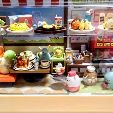 A miniature toy cafe with various figurines and miniature food items displayed on shelves and tables.