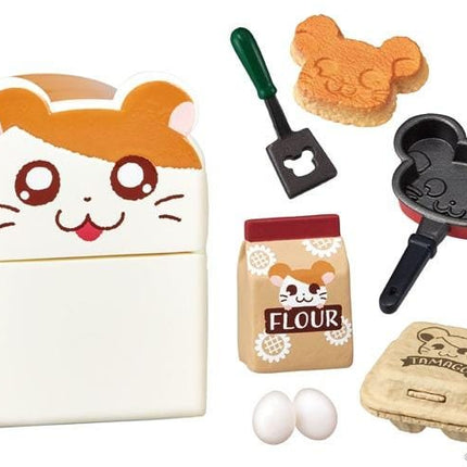 various kitchen-related items, including a hamster-shaped breadbox, a hamster-shaped spatula, a hamster-shaped whisk, a hamster-shaped frying pan, a bag of flour, and a carton of eggs.