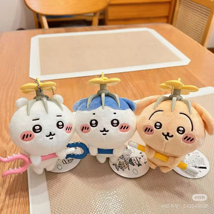 Plush mascot keychain set of three on table, white blue and tan characters