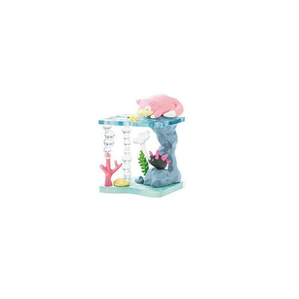 A pink and black toy figurine is sitting on a blue platform with various other toy figurines and accessories, including a pink fish, a pink coral, and a pink and blue striped toy.