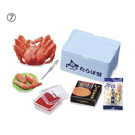 various food items and containers, including a large red crab, a blue styrofoam container, a green plate with red meat, a clear plastic container with red food, and a black box with Japanese text.