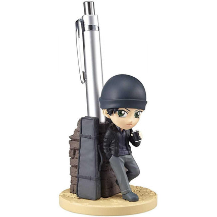 A figurine of a person leaning against a pen holder, wearing a hat and holding a pen.