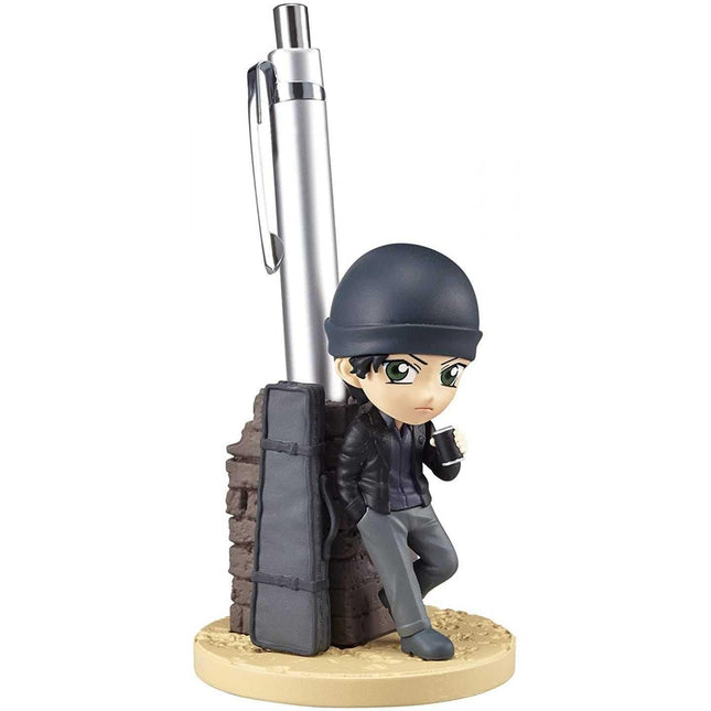 A figurine of a person leaning against a pen holder, wearing a hat and holding a pen.