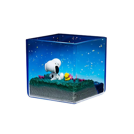A small glass container containing a miniature landscape with a white dog sitting on a grassy area, surrounded by colorful flowers and a starry night sky.