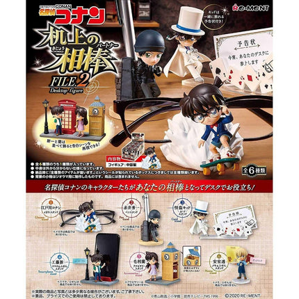 The image is a promotional advertisement featuring a collection of desk toys, including figurines of characters and miniature scenes. The toys are displayed in various settings, such as a desk, a street, and a building. The advertisement includes text in Japanese, which suggests that the toys are part of a limited edition collection.