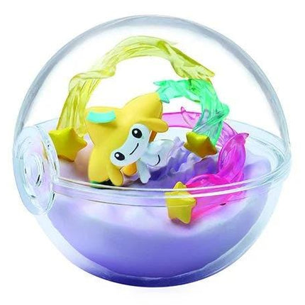 A transparent glass ball containing a miniature figurine of a yellow star and various other small figurines, including a purple star and a pink star.