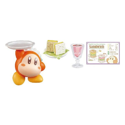 a small toy figurine of a character holding a plate with a sandwich on it, along with a glass of what appears to be a pink beverage. There is also a poster or sign with illustrations and text related to sandwiches.