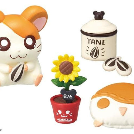 a variety of colorful and whimsical toys, including a hamster figurine, a sunflower, a potted plant, a small red pot, and a stuffed animal.