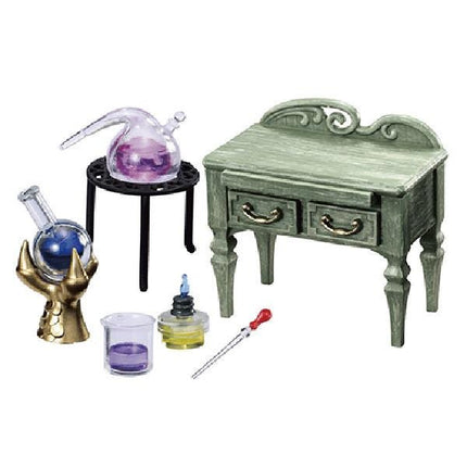 a miniature table with drawers, a glass beaker, a test tube, and a small figurine of a hand holding a crystal ball.