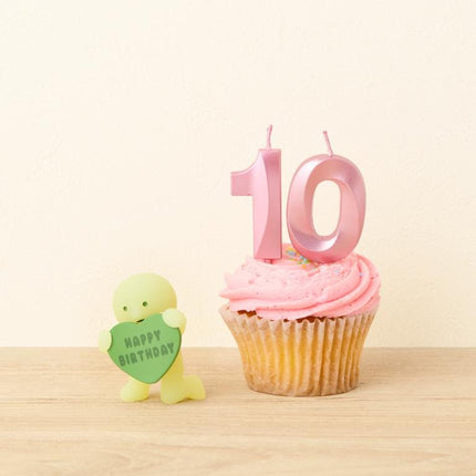 A cupcake with pink frosting and a number 10 candle, accompanied by a small green figurine holding a heart-shaped sign that says "Happy Birthday".