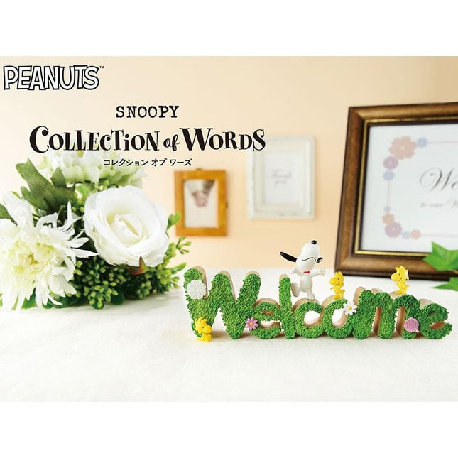a collection of words spelled out in green grass, with a framed picture of Snoopy and a bouquet of white flowers in the background.
