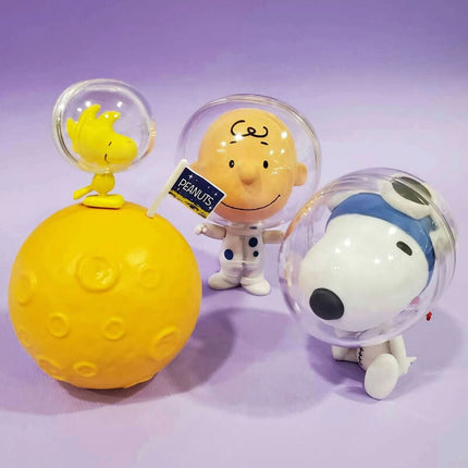 Set of 3 astronaut capsule toys: clear helmets with Snoopy, smiling face, and yellow trophy