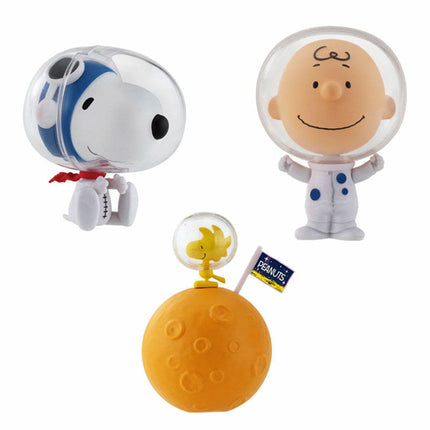 Three astronaut capsule toys with clear helmets: Snoopy, smiling character, and yellow trophy on ball