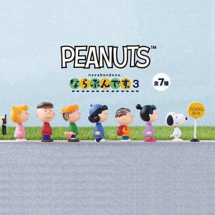 Seven Peanuts capsule toy figures, including Snoopy and characters with a school bus sign