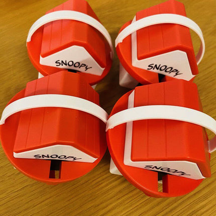 Four red capsule containers with white labels reading “SNOOPY”