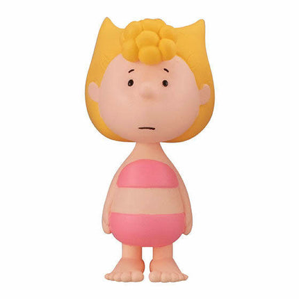 Peanuts-style girl figure with yellow hair, pink dress top, and yellow cone headpiece