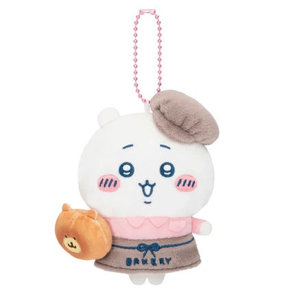 White bakery staff mascot plush with brown chef hat and pink beaded necklace