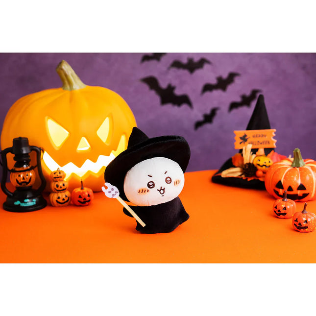 Plush mascot in black witch hat and red bow, holding a small wand prop