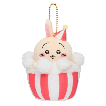 Beige bunny plush keychain with orange bead necklace, red party hat, and striped cupcake