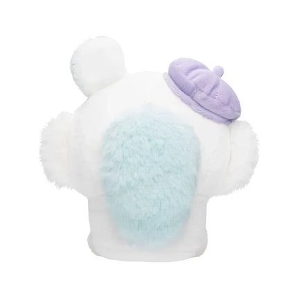 Back view of white sitting plush toy with purple hat and light blue patch