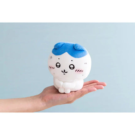 White-and-blue plush toy held in hand with blue cap and cute face