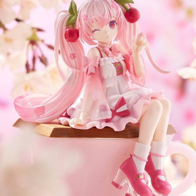 Sakura Miku 2025 noodle stopper figure, pink dress with ribbon bows, seated on base