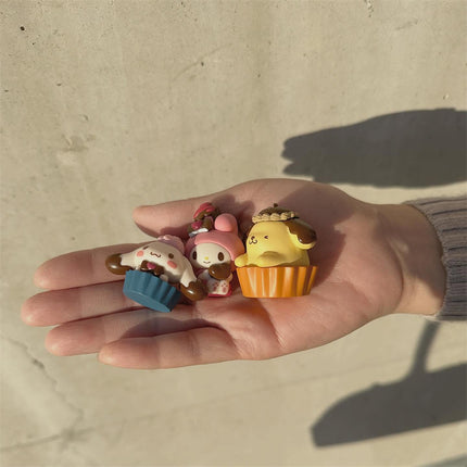 Three Sanrio chocolate character capsule dolls held in a hand, small chocolate figures