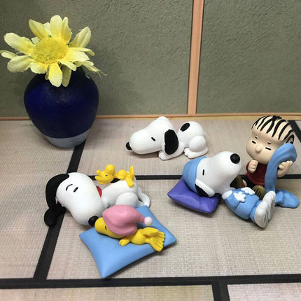 Snoopy sleeping figures set arranged on floor mats, including yellow chick and blue poses
