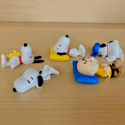 Snoopy sleeping figures set on wooden surface with blue and yellow sleeping mats
