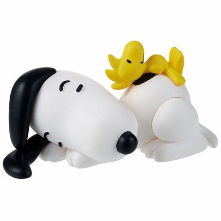 Sleeping Snoopy figure curled, holding a yellow chick; black ear and dark nose