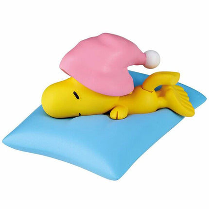Sleeping Snoopy figure on light-blue mat with yellow body and pink head cover