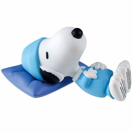 Sleeping Snoopy figure on blue mat wearing light-blue top; eyes closed, resting