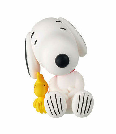 Snoopy capsule toy figure in white, lying with small yellow bird beside