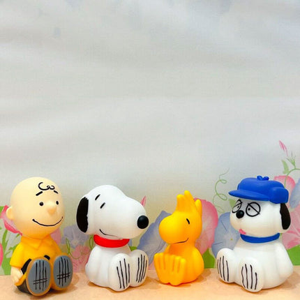 Group of four PEANUTS capsule toy figures: dog, boy, yellow bird, and blue-hat dog.