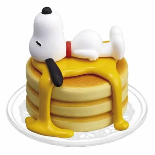 Yellow layer cake capsule figure with Snoopy lying on top, on white plate