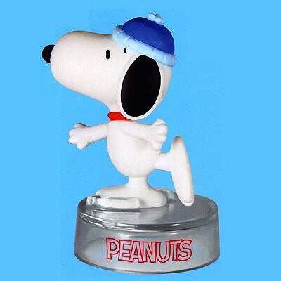 Peanuts Snoopy figure with blue cap and open mouth, posed on round "PEANUTS" base