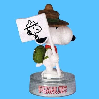 Peanuts Snoopy figure with brown cap, holding a white sign, on round "PEANUTS" base