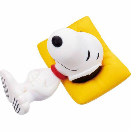 Snoopy capsule mascot figure sleeping on a yellow pillow with red collar