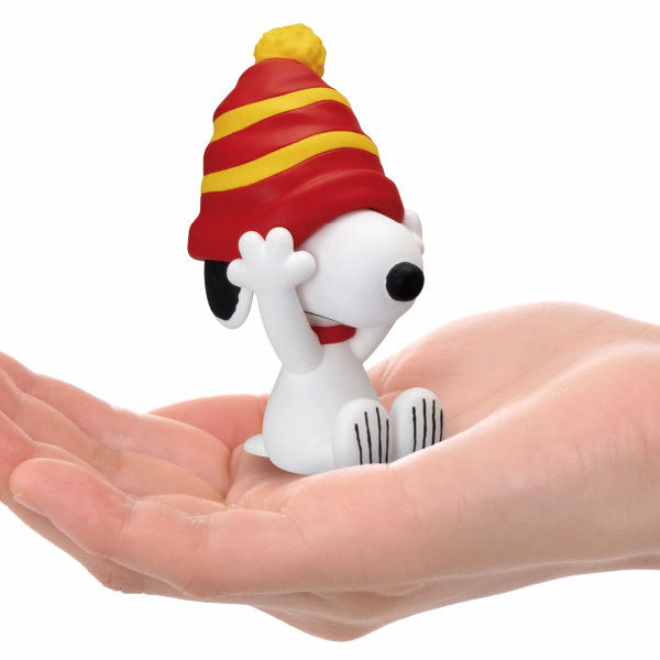Snoopy hide-and-seek figure with red and yellow striped hat, sitting on open hand