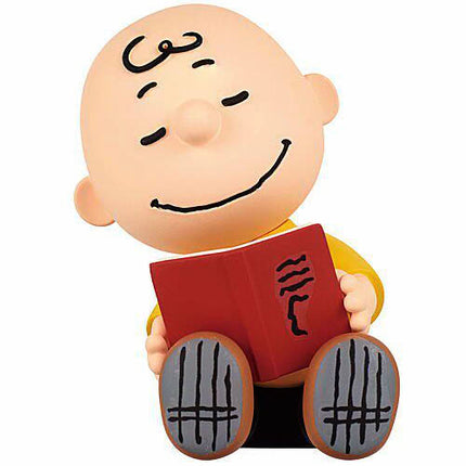 Charlie Brown sleeping capsule toy figure holding a red book