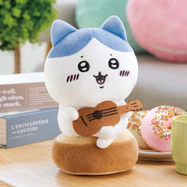 Blue-and-white plush cat toy sitting and playing a brown acoustic guitar