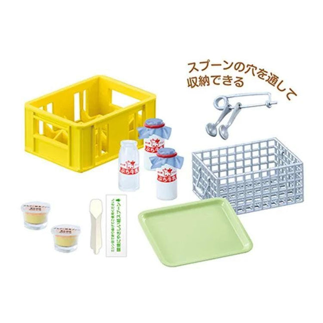 various food items and utensils, including a yellow plastic crate, a green tray, a pair of scissors, and some containers. There is also a sign with Japanese text, which appears to be a price tag or label.