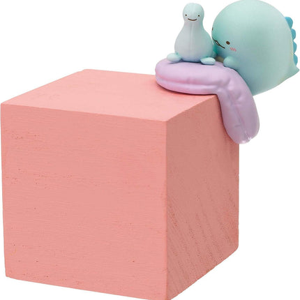 A pink wooden block with two small, colorful figurines sitting on top of it.