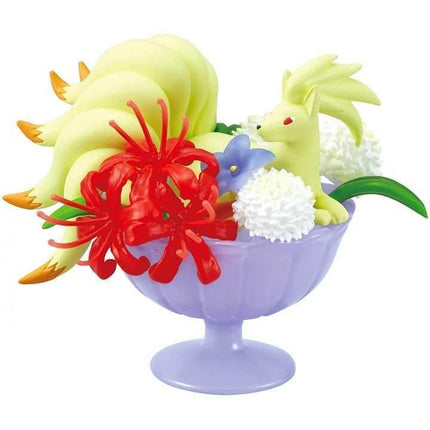 A purple vase containing a variety of colorful flowers and a yellow figurine.