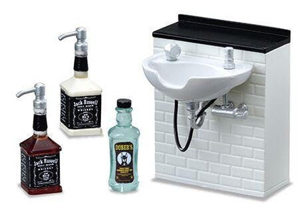 A miniature bathroom set with a sink, soap dispenser, and three bottles of alcohol.