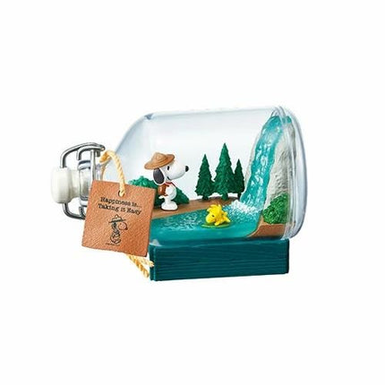 A Peanuts-themed miniature diorama in a glass bottle, featuring a Snoopy character in a hat, a waterfall, and a small yellow duck.